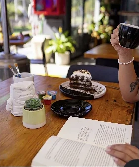 Café, torta y un libro abierto junto a pinceles y un yeso