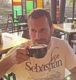 Un cliente toma café junto a los ventanales de colores