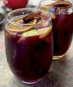 Dos copas de sangría con naranja deshidratada y canela