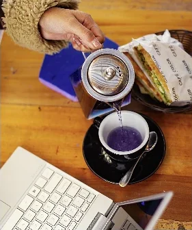 Tetera sirviendo la infusión morada Viaje mágico junto a un sándwich